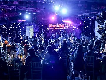 A room full of people sit for food at their christmas party