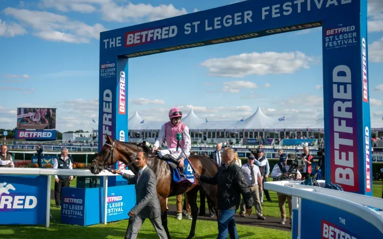 Horse and jockey being led under an archway for the Leger Festival
