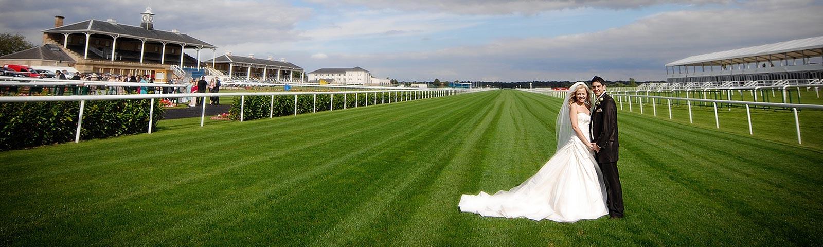 A bride and groom pose for a photograph on the race track at Doncaster Racecourse.