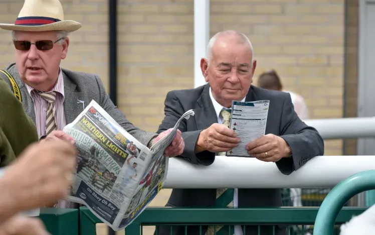 Race goers study the racecard and racing post at Doncaster
