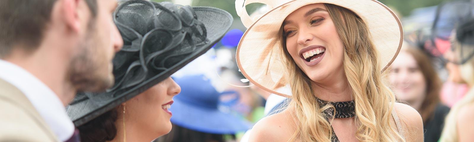 Woman smiles to her friend while wearing an extravagant hat