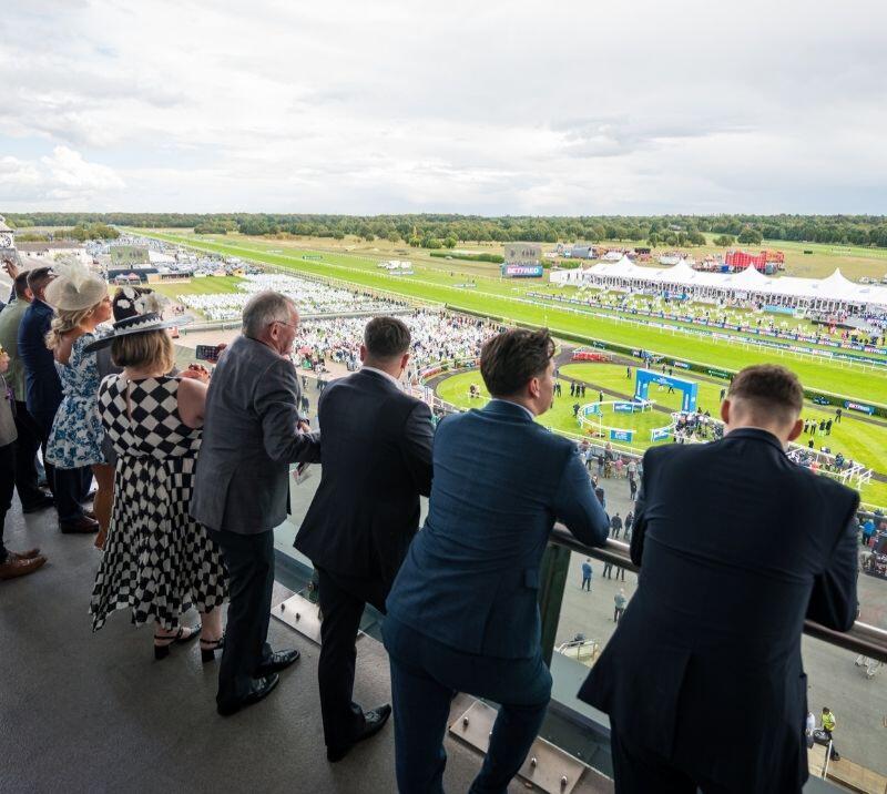 Views from balcony of the racecourse with racegoers looking out onto the course