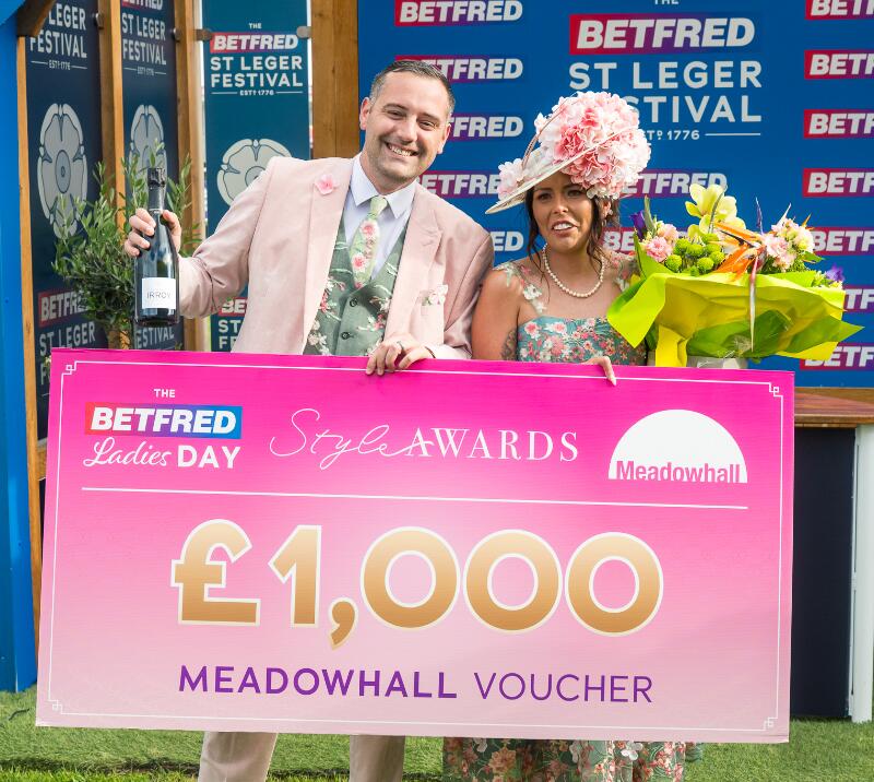 Two winners of the 2026 Doncaster Racecourse Style Awards holding a £1000 Meadowhall voucher, flowers, and champagne.
