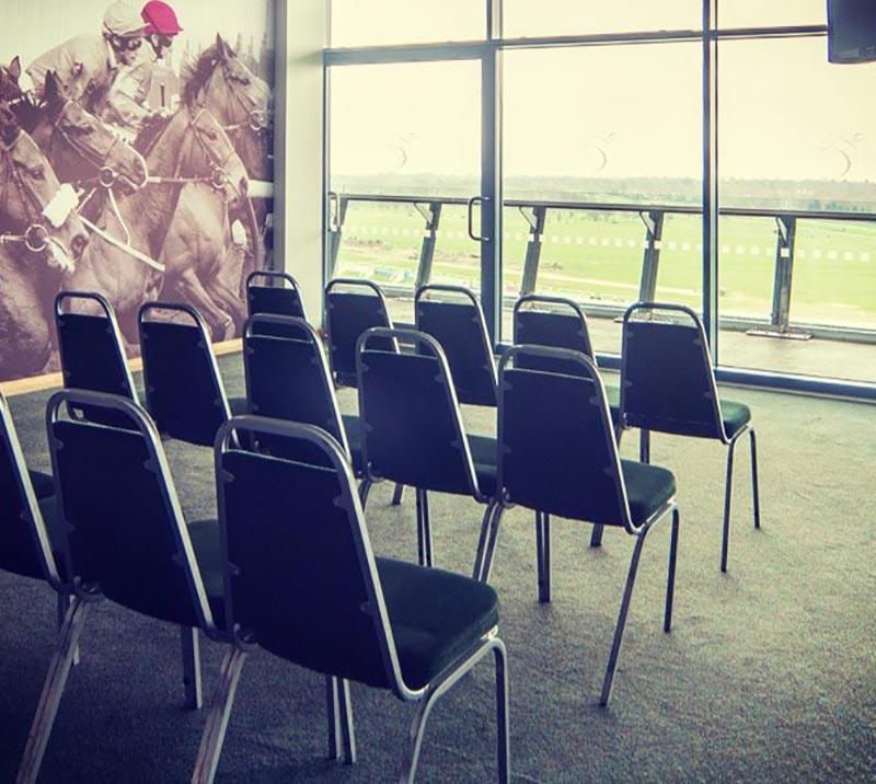 3 rows of 5 black chairs facing the window overlooking the race track.