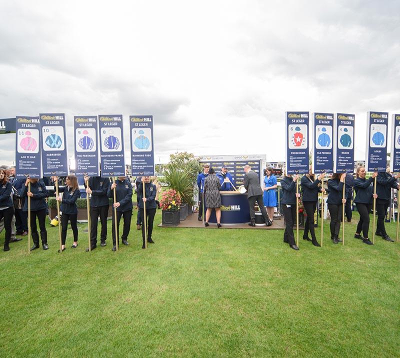 Staff of Doncaster Racecourse hold sign posts up advertising the available horses for betting
