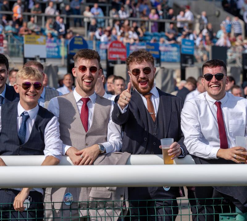 A young group of guys in suits at the races