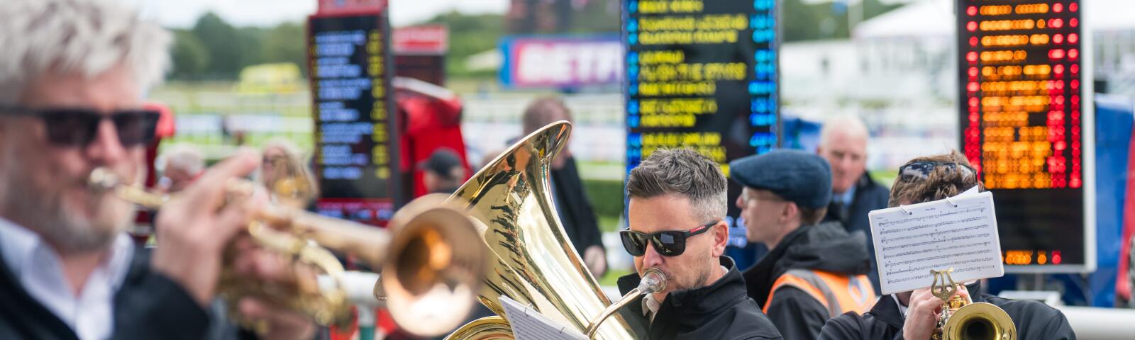 Live musicians play in front of betting boards at Doncaster Races