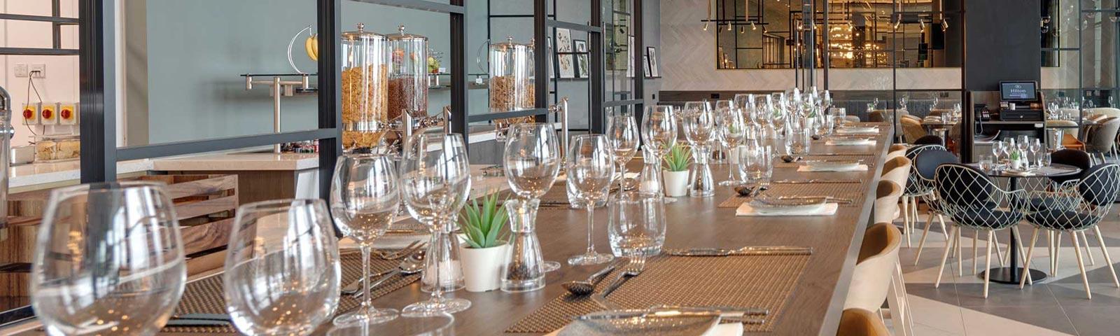 A large dinning table decorated with glasses and place mats